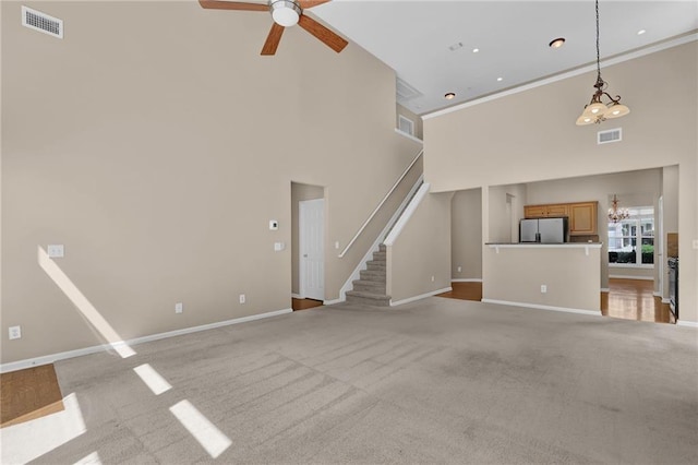 5040 Stonehaven Vw, Cumming, GA 30040 - unfurnished living room with a chandelier, a ceiling fan, a towering ceiling, baseboards, and light carpet