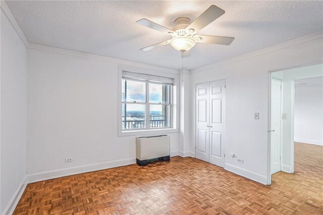 spare room featuring parquet flooring, a textured ceiling, ceiling fan, and crown molding