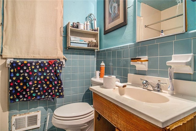 bathroom featuring visible vents, tile walls, toilet, and vanity