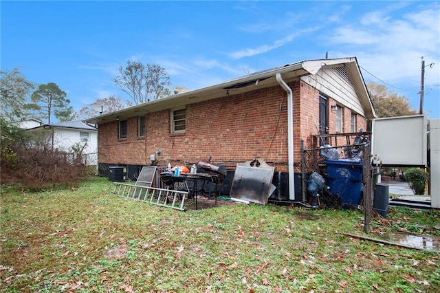 back of house featuring brick siding, a lawn, and cooling unit