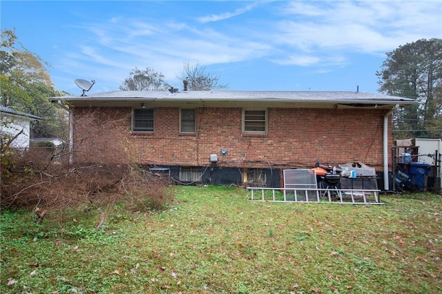 rear view of property with a lawn and brick siding