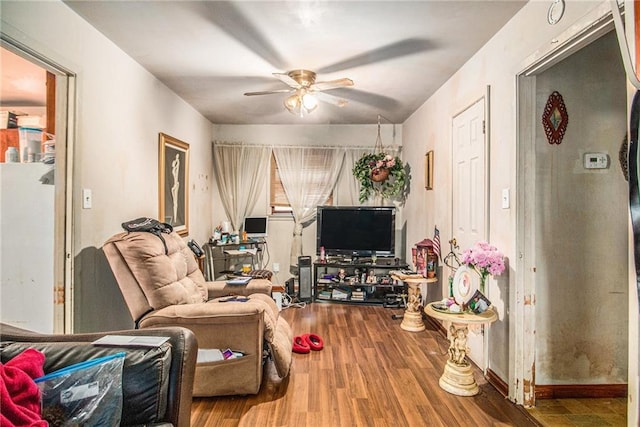 living area with baseboards, a ceiling fan, and wood finished floors