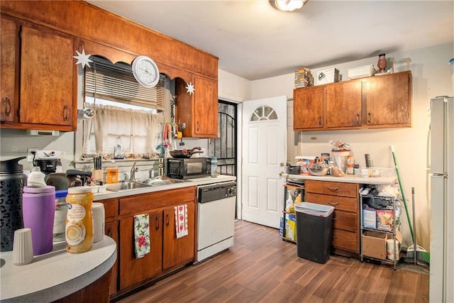 kitchen with white appliances, dark wood-type flooring, a sink, light countertops, and brown cabinetry