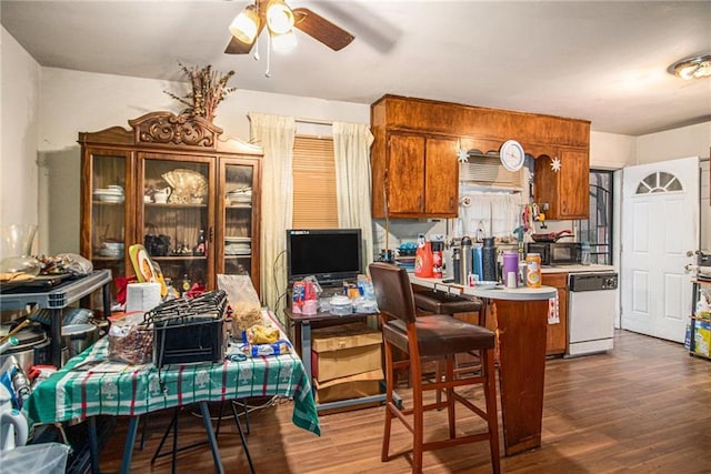 kitchen featuring dark wood finished floors, light countertops, brown cabinetry, black microwave, and dishwashing machine