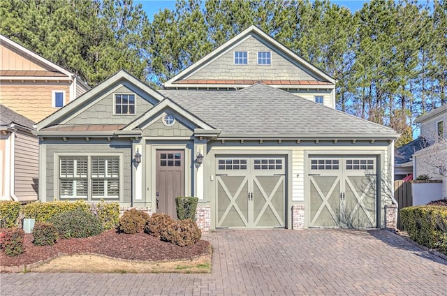 view of front of home with a shingled roof, decorative driveway, and an attached garage