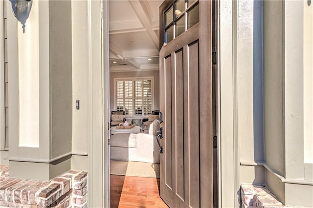 corridor featuring light wood-style floors, ornamental molding, coffered ceiling, and beamed ceiling