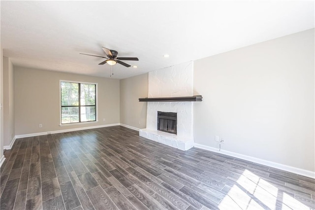 unfurnished living room featuring ceiling fan, dark wood finished floors, baseboards, and a premium fireplace