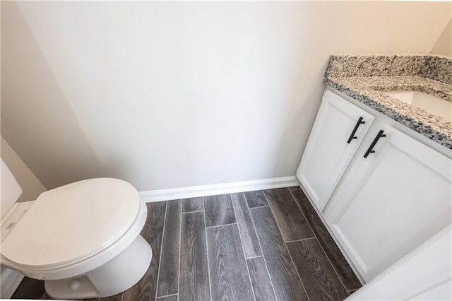 bathroom with wood finish floors, toilet, vanity, and baseboards