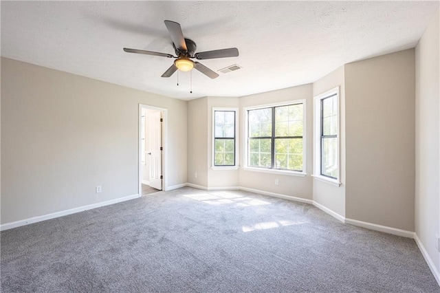 unfurnished room featuring visible vents, baseboards, a ceiling fan, carpet, and a textured ceiling