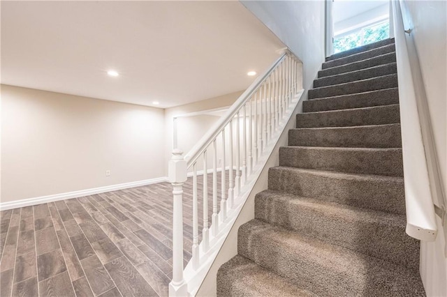 stairs with baseboards, wood finished floors, and recessed lighting