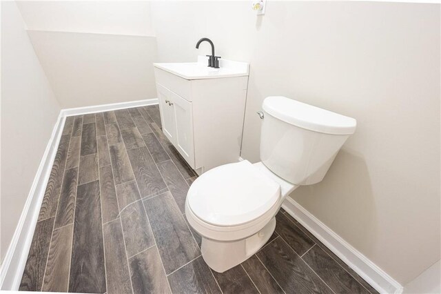 bathroom featuring toilet, wood tiled floor, baseboards, and vanity