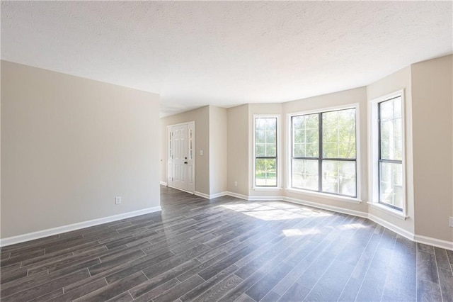 spare room with dark wood-style floors, baseboards, and a textured ceiling