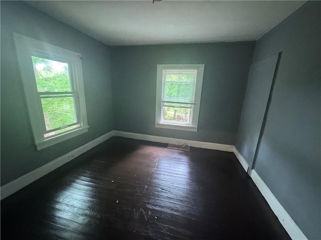 spare room featuring baseboards and dark wood finished floors