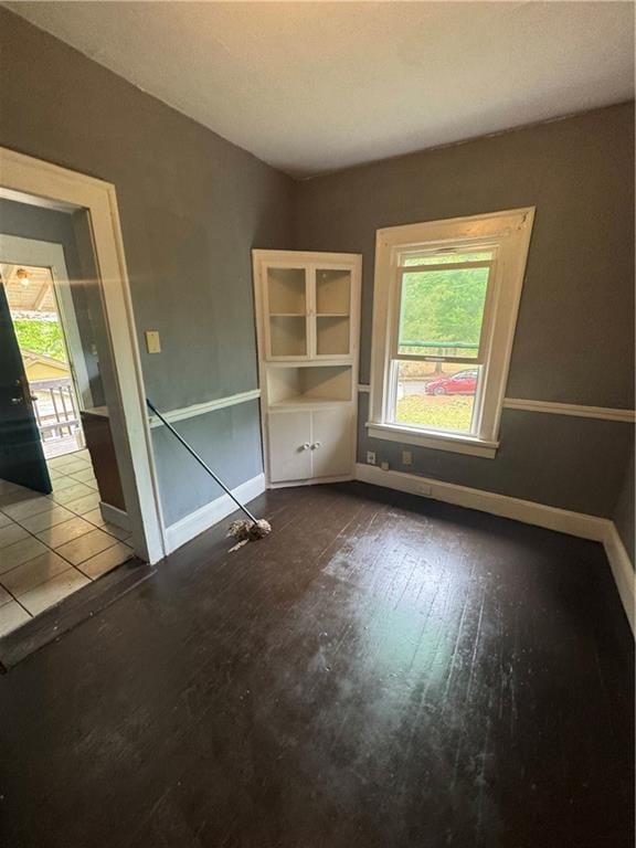unfurnished room with baseboards and wood-type flooring
