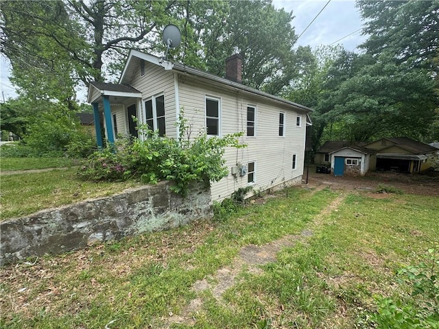 view of side of property with an outbuilding, a yard, and a chimney