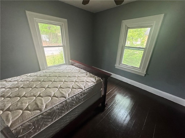bedroom with dark wood-style flooring, baseboards, multiple windows, and a ceiling fan
