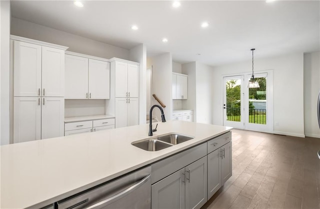 kitchen featuring hanging light fixtures, sink, dark wood-type flooring, white cabinetry, and dishwasher