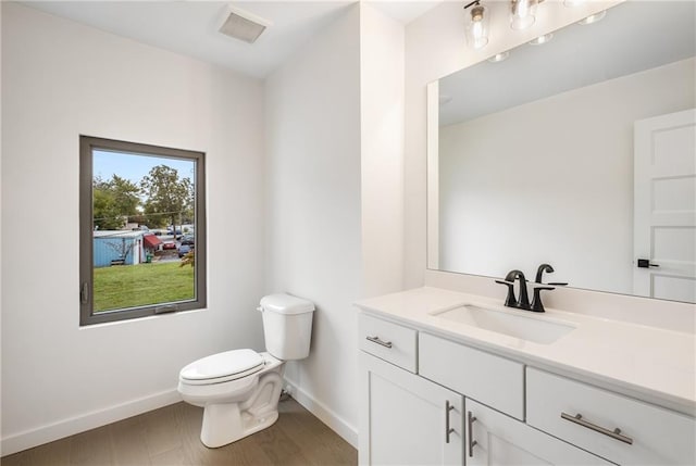 bathroom with toilet, vanity, and wood-type flooring