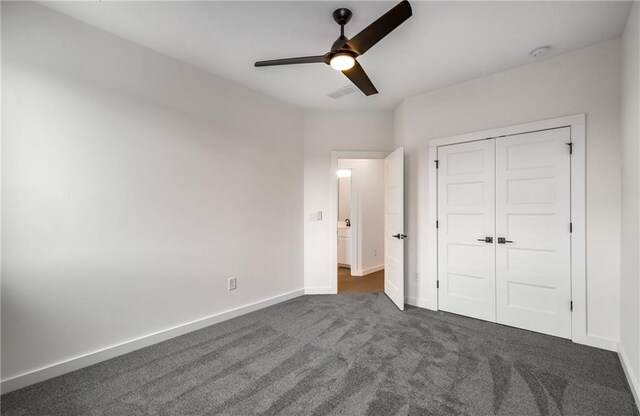 unfurnished bedroom featuring ceiling fan, a closet, and dark carpet