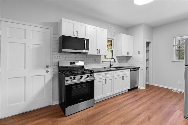 kitchen with sink, white cabinetry, appliances with stainless steel finishes, and plenty of natural light