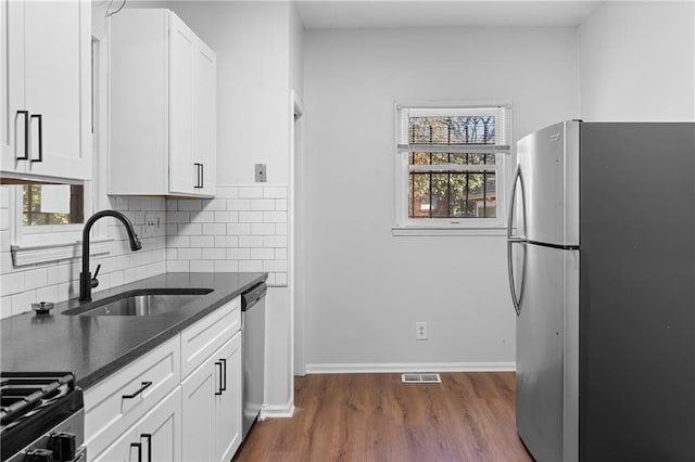 kitchen with appliances with stainless steel finishes, white cabinetry, decorative backsplash, sink, and plenty of natural light