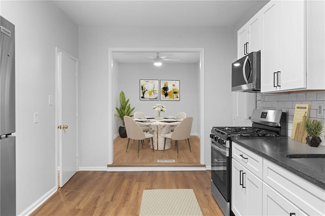 kitchen featuring ceiling fan, backsplash, white cabinetry, light wood-type flooring, and stainless steel appliances