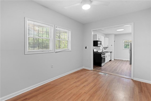 kitchen with light hardwood / wood-style flooring, sink, white cabinets, tasteful backsplash, and stainless steel appliances