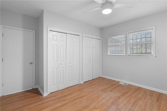 unfurnished bedroom with multiple closets, light wood-type flooring, and ceiling fan