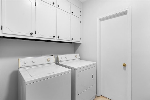 washroom featuring cabinets and washer and clothes dryer