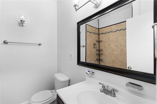 bathroom featuring toilet, vanity, and a tile shower