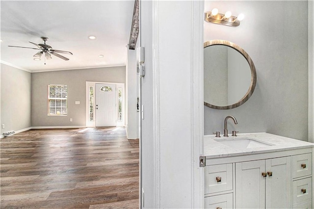 bathroom with ornamental molding, vanity, vaulted ceiling, ceiling fan, and hardwood / wood-style flooring