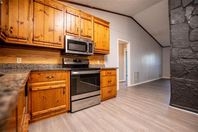 kitchen featuring vaulted ceiling, stainless steel appliances, and light wood-type flooring