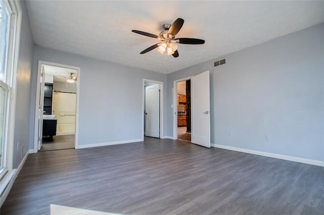 unfurnished bedroom with ensuite bathroom, dark wood-type flooring, and ceiling fan