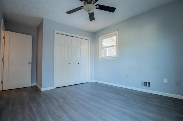 unfurnished bedroom with dark hardwood / wood-style floors, ceiling fan, and a closet