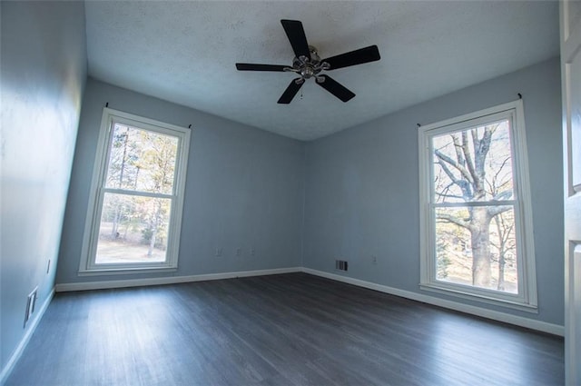 spare room featuring ceiling fan, dark wood-type flooring, and a healthy amount of sunlight