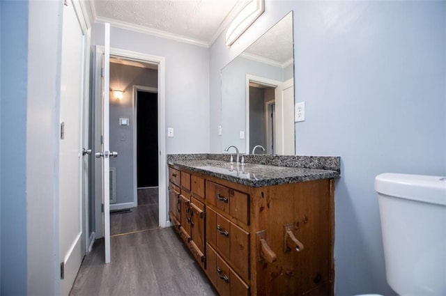 bathroom with vanity, hardwood / wood-style floors, ornamental molding, and toilet