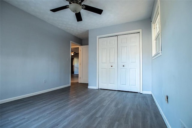 unfurnished bedroom featuring dark wood-type flooring, a textured ceiling, ceiling fan, and a closet