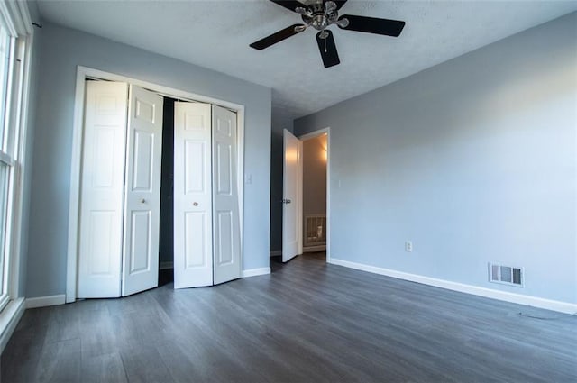 unfurnished bedroom featuring dark wood-type flooring, a closet, and ceiling fan