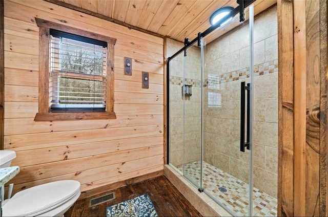 bathroom with a shower stall, wooden walls, toilet, wood finished floors, and wooden ceiling