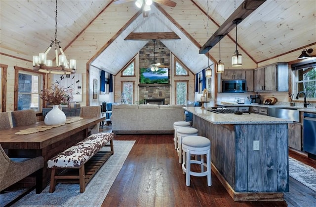 kitchen featuring stainless steel microwave, a sink, dark wood finished floors, a ceiling fan, and wood ceiling with exposed beams