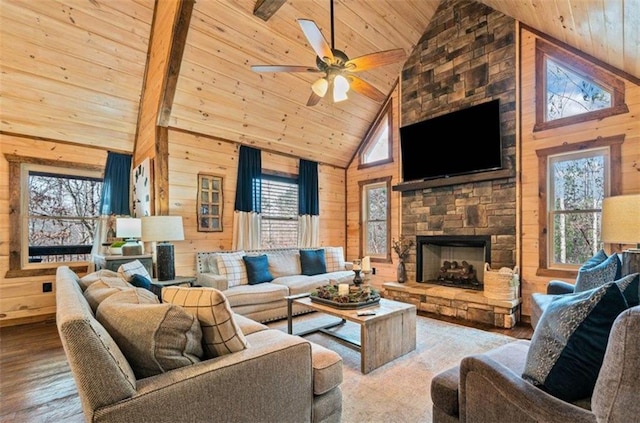 living room with wooden ceiling, wooden walls, wood finished floors, a ceiling fan, and a fireplace