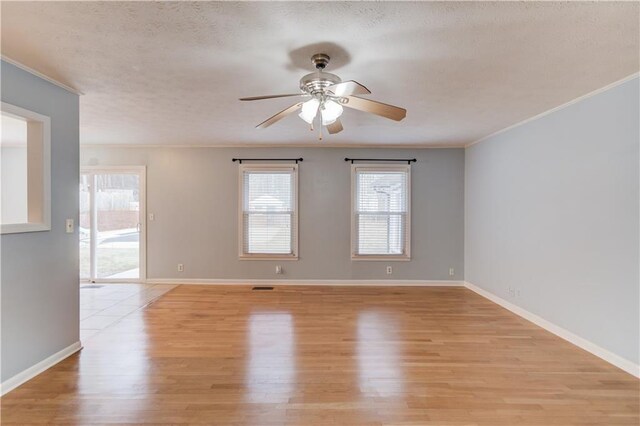 empty room featuring a ceiling fan, light wood-style flooring, visible vents, and baseboards