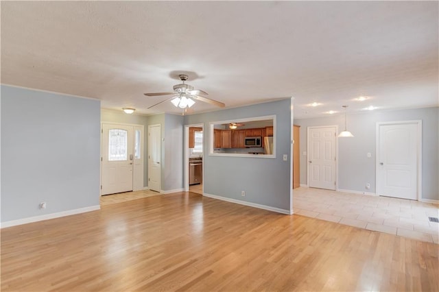 unfurnished living room featuring light wood-type flooring, baseboards, and a ceiling fan