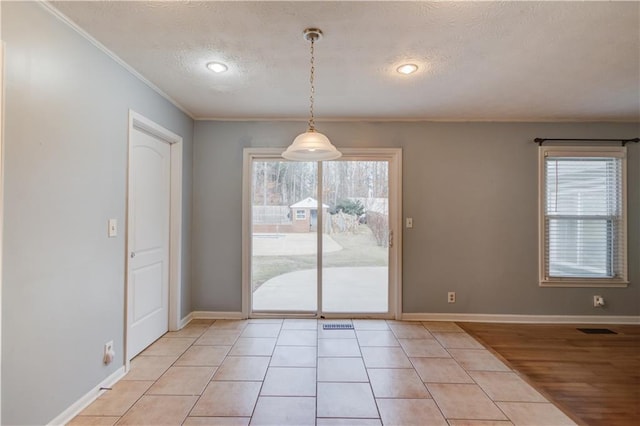 unfurnished dining area with light tile patterned floors, visible vents, baseboards, ornamental molding, and a textured ceiling