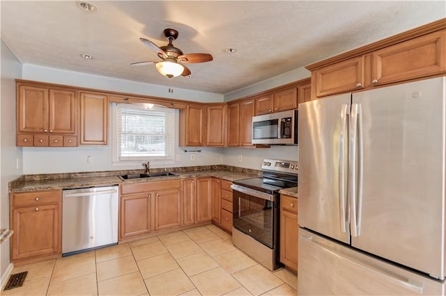 kitchen with appliances with stainless steel finishes, brown cabinetry, and a sink