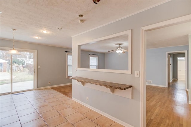 spare room with a textured ceiling, crown molding, visible vents, and baseboards