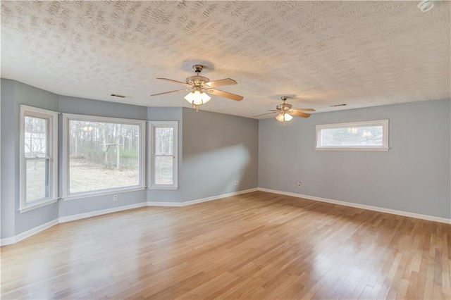 empty room featuring light wood-type flooring, baseboards, and a textured ceiling