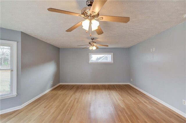 spare room featuring a ceiling fan, light wood-type flooring, a textured ceiling, and baseboards