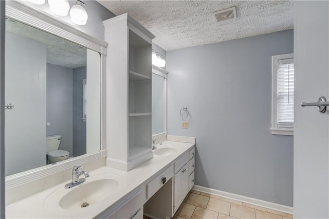 full bathroom featuring toilet, a textured ceiling, visible vents, and a sink