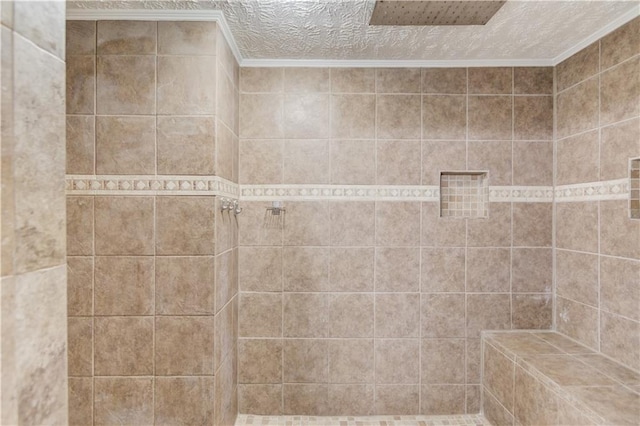 bathroom with ornamental molding, a tile shower, and a textured ceiling